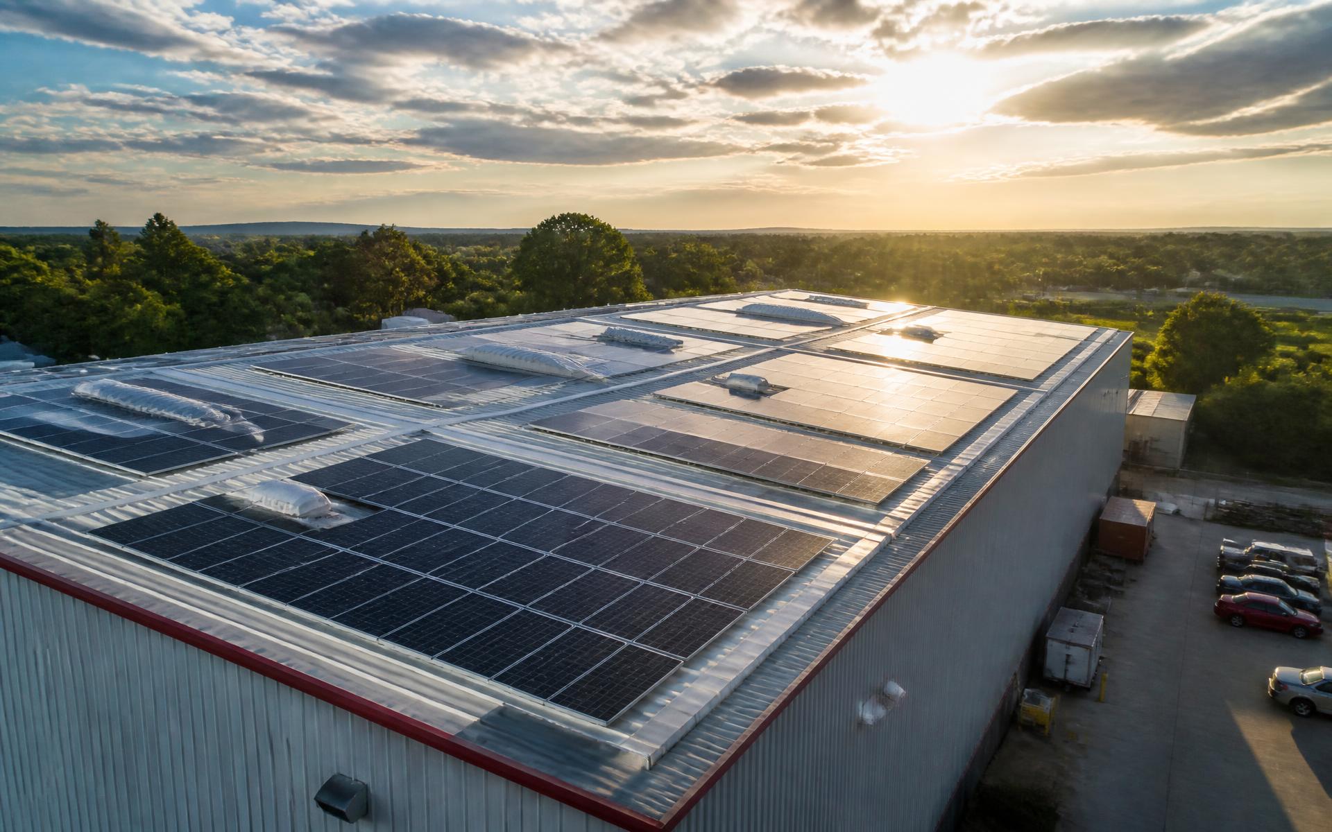Wide rooftop solar installation photographed under dramatic sunlight